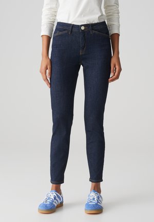 Dunkelblaue Skinny-Jeans mit klassischem 5-Taschen-Design, aus Denim-Tuch gefertigt, mit orangefarbenen Nähten und einem Frontknopfverschluss.