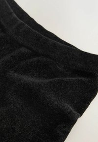 Black fabric, soft texture, with a slight sheen. The edge is smooth, revealing a rich, plush surface and subtle variations in fiber density.