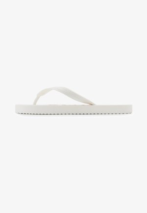 White flip-flop with a flat, textured sole and Y-shaped thong straps. The sole has a wavy edge, providing a simple, minimalistic design.
