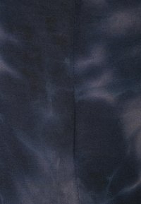 Tkanina s námořnickou modrou batikou a hladkým povrchem. Vzor obsahuje víry světlejších odstínů, které vytvářejí jedinečný designový prvek.