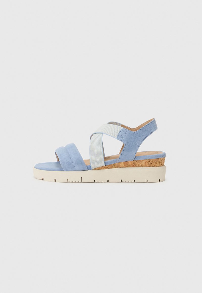 Sandales à semelle compensée avec une tige en suédine bleu clair, une sangle croisée en tissu, un intercalaire en liège et une semelle en caoutchouc blanche. Design plat et ouvert à l'arrière.