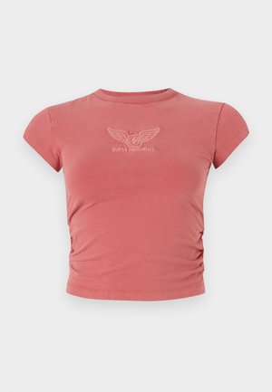 Kortærmet, tætsiddende t-shirt i støvet rosa med samlet sideløsning og broderet "GUESS ORIGINALS" logo i hvid på brystet.
