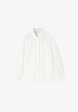Bijela pamučna košulja s kragnom i dugim napuhanim rukavima, ukrašena hipo vezenim detaljima, koja prikazuje glatku teksturu.
