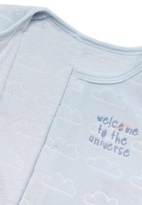 Un bodysuit para bebé de color azul claro, hecho de una tela suave, con patrones de nubes y texto bordado: "bienvenido al universo". Con cierres a presión en la parte delantera.