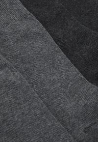 Dunkelgraue und schwarze Socken mit einer weichen Textur, die ein glattes Strickdesign aufweisen und in verschiedenen Farbtönen sowie mit einem gerippten Bund gestaltet sind.