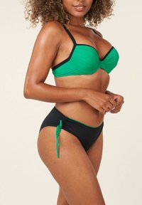Haut de bikini vert avec des accents noirs ; texture côtelée et design avec armatures. Bas de bikini noir avec un détail de cordon vert sur le côté.