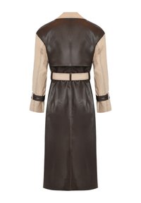 Trench-coat long bicolore avec corps en cuir marron foncé, manches beige, taille ceinturée et détails à sangles aux poignets, vu de dos.