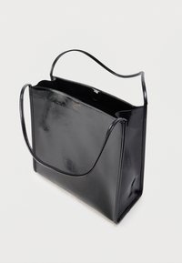 Czarna torba typu tote wykonana ze skóry o gładkiej fakturze, prosta, prostokątna forma, otwarty wierzch oraz dwa długie uchwyty do noszenia.