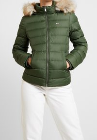 Zielona kurtka ocieplana z zamkiem z przodu, odpinanym futrzanym kapturem i bocznymi kieszeniami. Posiada pikowaną fakturę i subtelne logo marki.