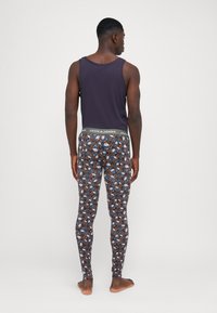 Men's sleeveless purple top paired with fitted leggings featuring a multicolored fox and floral pattern, with a gray elastic waistband.