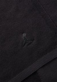 Črna pletena šalica z rebrasto teksturo in majhnim črnim Jumpman logotipom izvezenim na materialu. Obrobljena z gladkim pletenim robom.
