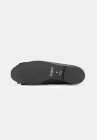 Semelle d'une chaussure noire Gabor taille 5, montrant un talon plat et une semelle texturée sur fond gris uni.