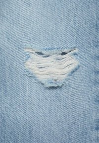 Tessuto in denim azzurro chiaro con una toppa sfrangiata, caratterizzato da uno strappo orizzontale bordato di fili bianchi, che crea un aspetto vissuto.
