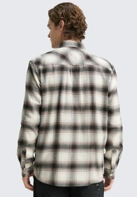 Karierte Flanellhemd in Creme, Schwarz und Rot mit langen Ärmeln, geknöpften Manschetten und klassischem Kragen. Warmes, strukturiertes Material.