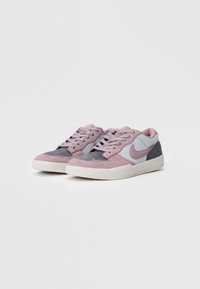 Par av lave sneakers med rosa og grå semsket skinnpaneler, hvite såler og rosa snøringer på en enkel hvit bakgrunn.