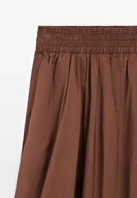 Brown, pleated skirt with an elastic waistband. Made from lightweight fabric with a smooth texture and a solid color.