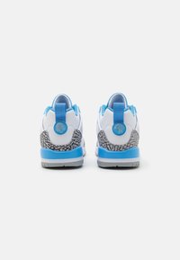 Zapatillas blancas con acentos azules y un talón texturizado con un patrón gris. Presentan una cinta para tirar y un logotipo redondo en la parte trasera. Suela de goma.