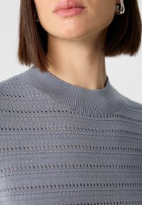 Hellgrauer Pullover mit einem strukturierten Design, horizontalen Streifen und kleinen offenen Strickdetails. Der gerippte Kragen verleiht dem GanzenDefinition.