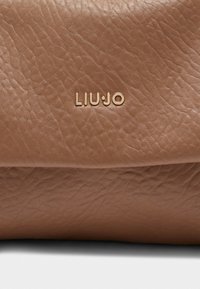 Borsa in pelle marrone con finitura testurizzata. Presenta il logo "LIU•JO" impressa in oro. Design compatto con parte superiore piegata e senza hardware visibile.
