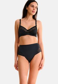 Zwarte lingerieset bestaande uit een beha met kanten accenten en beugel, gecombineerd met hoog uitgesneden slipjes met kanten details aan de zijkanten.
