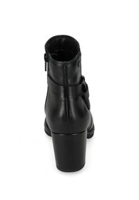 Stivale alla caviglia con tacco nero realizzato in pelle liscia. Presenta una chiusura con zip e una fascia testurizzata attorno alla caviglia. Punta rotonda e tacco spesso.