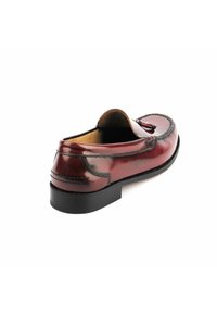 Mocasin de cuero en burdeos oscuro con punta redondeada, costuras elevadas como acentos y una suela negra plana. Textura suave, elementos de diseño mínimos.