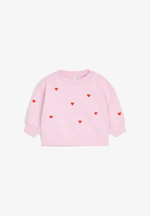 Sweat-shirt bébé à manches longues rose clair avec petits motifs de cœurs rouges dispersés sur le devant et les manches, avec boutons-pression sur une épaule.