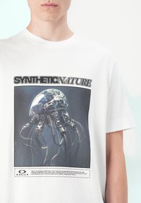 White cotton t-shirt featuring a graphic print of a metallic jellyfish with tentacles and the text "SYNTHETIC NATURE" above.