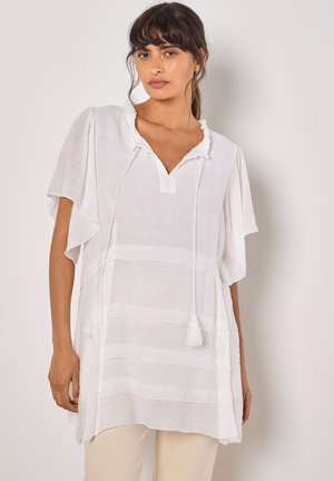 Weiße, leichte Tunika mit V-Ausschnitt, Rüschenschnitt, kurzen Ärmeln und horizontal gestreiftem Muster. Sie verfügt über einen Kordelzug mit Quasten.