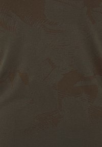 Dark brown textured fabric featuring a subtle pattern, with varying shades creating depth, suitable for clothing or upholstery use.