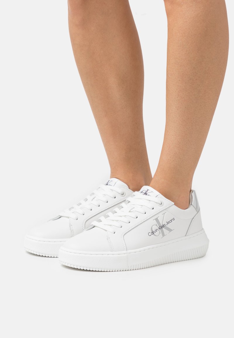 Sneaker bianchi in pelle di Calvin Klein con chiusura con lacci, suola in gomma testurizzata e dettaglio del logo sul lato. Design liscio e elegante.