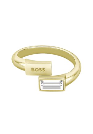 Anello in tono oro con una pietra trasparente rettangolare e un blocco rettangolare inciso con la scritta "BOSS," design elegante e lucido.