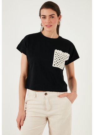 T-shirt noir court à manches courtes, avec un détail de poche en crochet blanc sur le côté gauche. Texture en coton lisse.