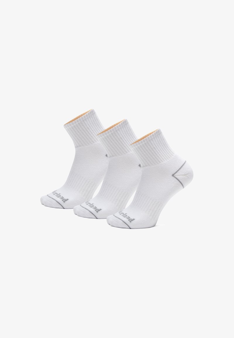 Bílé kotníkové ponožky s ribovanou strukturou, s kontrastním tan rukávem a šedým logem na špičce. Balení obsahuje tři páry.