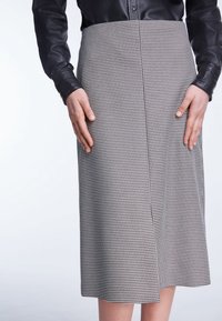 Zwart-witte houthakkers pencil skirt, knie-lang, met een split aan de achterkant, een gladde textuur en een nauwsluitende pasvorm, gedragen met een zwart leren top.