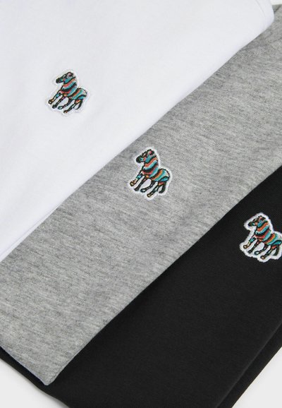 Tre t-shirt in tessuti bianco, grigio e nero. Ognuna ha un logo di zebra ricamato colorato in evidenza sul petto.