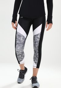 Svart och vita atletiska leggings med texturerade grå detaljer, med en åtsittande design och kontrasterande triangulära paneler.