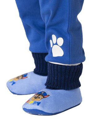 Soft blue slippers with a cartoon dog design, navy ribbed ankle cuffs, and a white paw print on dark blue pants.