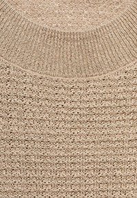 Beige striktrøje med et tekstureret mønster og ribbet rund halsudskæring. Blødt materiale med en let metallisk glans.