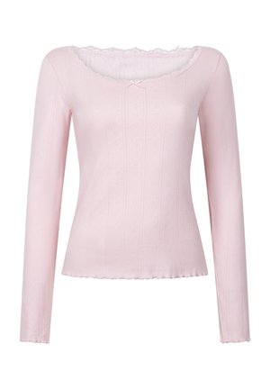 Haut à manches longues en tissu rose doux, avec un col festonné, un motif texturé et un petit nœud décoratif sur la poitrine.