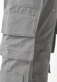Shorts cargo gris avec plusieurs grandes poches, tissu robuste, coutures visibles et une petite étiquette de marque sur le côté.