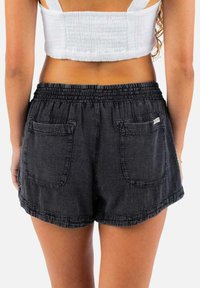 Zwarte denimshorts met een elastische tailleband, twee achterzakken en een casual snit. De stof heeft een gestructureerde uitstraling.