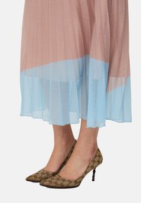 Pleated dress in pink and light blue, with a flowing design. Brown patterned high heels with a pointed toe and thin heel.