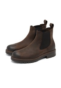 Botas Chelsea de cuero marrón con paneles laterales elásticos, punteras redondeadas y suelas de goma gruesa. Cuentan con tiradores para facilitar su puesta.