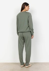 Olijfgroen loungewear-set, met een lange mouw top en relaxte broek met elastische tailleband. Zachte stof met minimale textuur.