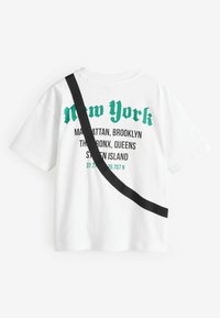 Witte katoenen T-shirt met groene tekst die "New York" en de namen van de stadsdelen bevat, met een zwarte diagonale band over de voorkant.