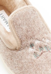 Beige vilten slof met een zachte textuur; voorzien van een geborduurd ontwerp van bergen en bomen in groen en bruin; instapstijl met een ronde rand.