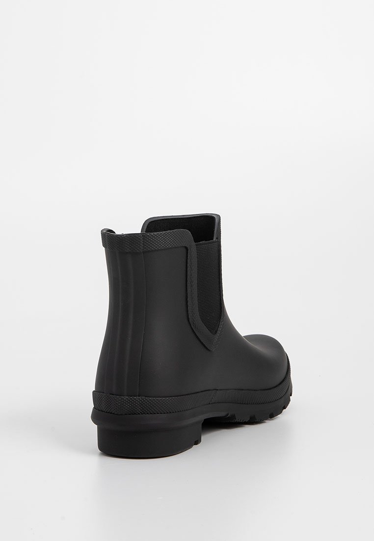 Botas de goma negras hasta el tobillo con paneles laterales elásticos, punta redonda, suela texturizada y superficie lisa. Adecuadas para condiciones de clima húmedo.