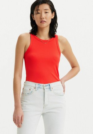 Top de tirantes rojo acanalado con escote redondo, combinado con jeans de cintura alta de color azul claro. Textura suave con diseño ajustado.