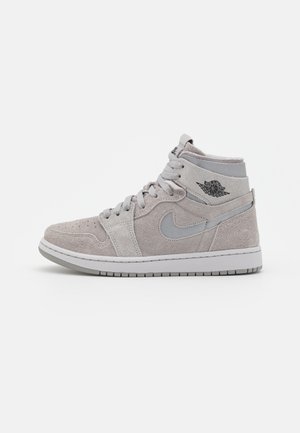 Jasnoszare zamszowe sneakersy za kostkę z logo Nike swoosh, logiem Air Jordan wings na kostce oraz sznurowadłami na białym tle.